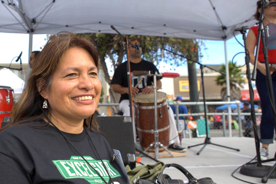 A City College alumni and the music coordinator of 12th Annual Excelsior Art & Music Festival, Rosario Cervantes, stands in front of the music stage while Puerto Rican music band ‘La Mixta Criolla’ performs at the Sunday Streets Festival in The Excelsior, San Francisco on Sunday, Sept. 28, 2014. Each year Sunday Streets collaborates with the Excelsior Art & Music Festival to bring fun activities to the community. (Photo by Ekevara Kitpowsong)