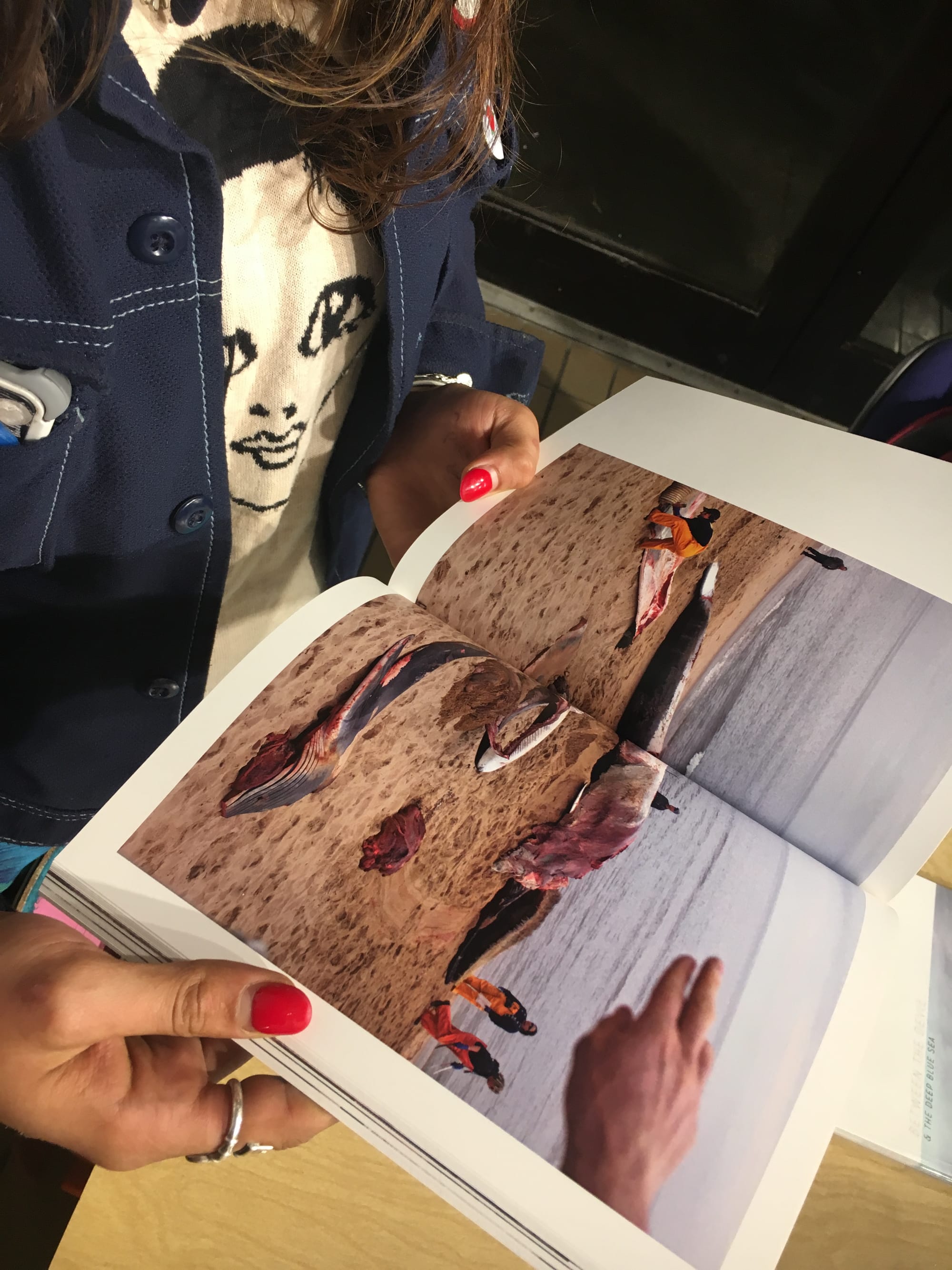 CCSF photography student Rebecca Diablo stares at a whale carcass photo in Preston Gannaway’s visual essay book, “Between the Devil and the Deep Blue Sea” on September 6, 2017. (Photo by Laurie Maemura) 