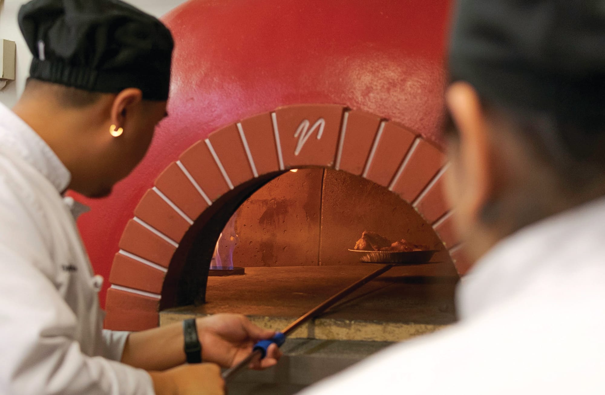 Cindy Serrano, right, watches Dillon Takao, left, slot the chicken wings into the oven at 900 degree Fahrenheit in approximately two minutes on September 6, 2018. 